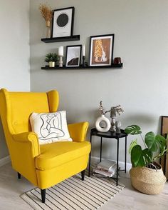 a living room with yellow chairs and pictures on the wall