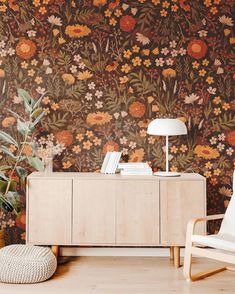 a living room with floral wallpaper and a white chair in front of the sideboard