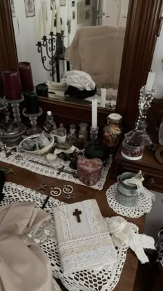 the table is covered with many items and has a cross on it in front of a mirror