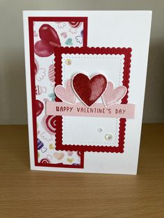 a valentine's day card with hearts and ribbon on the front, sitting on a table