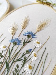 some white and blue flowers are in the embroidery