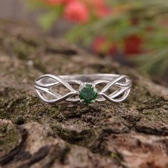 a ring with a green stone in the middle on top of a tree trunk,