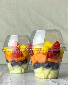 two plastic containers filled with fruit on top of a table