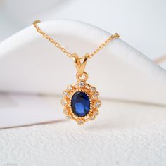 "Illuminate elegance with our Silver Filled 14K Gold Blue Sapphire Necklace - a piece where vintage charm meets contemporary allure. Each necklace, exclusively available in a silver-filled 14K gold setting, flaunts a striking oval blue sapphire, complemented by a resplendent halo of white cubic zirconia. An emblem of timeless love and perfect for every occasion, it's the quintessential gift for her, ensuring you deliver not just a beautiful jewel but a cherished moment wrapped in sophistication and timeless style. Embrace elegance that never fades with this enchanting, versatile piece. The sapphire is the birthstone for the month of September. It's valued for its vibrant blue color and is thought to bring wisdom and protection to those who wear it. Sapphire is also traditionally given as a Necklace Blue Stone, 70th Wedding Anniversary, Blue Stone Necklace, Blue Sapphire Necklace, Vintage Elegance, Necklace Blue, Sapphire Necklace, Sapphire Jewelry, Necklace Vintage