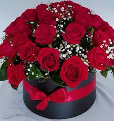 a bouquet of red roses in a black box