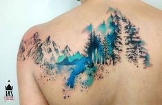 the back of a man's shoulder with trees and mountains painted on his chest