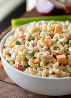 a white bowl filled with macaroni salad on top of a wooden table