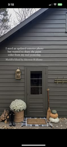 the front door of a gray house with two baskets and brooms on the ground