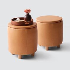 two small stools with a vase on one and a tray on the other side