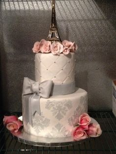 a three tiered cake decorated with pink roses and an eiffel tower on top