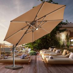 an open umbrella on top of a wooden deck next to couches and tables with pillows