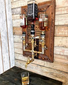 an old fashioned wall mounted liquor dispenser with three glasses on the side