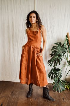 Rust Cara Pinny dress. Beautiful adjustable cross back with elastic waist band.  Pockets High grade lightweight cotton Suitable for size 6-12 Casual Backless Dress With Lace-up Back, Brown Smocked Back Sundress, Brown Sundress With Smocked Back, Cotton A-line Dress With Tie Back, Brown Dress With Smocked Back For Daywear, Casual Cotton Sundress With Smocked Back, Brown Tie-back Dress For Spring, Casual Cotton Backless Dress, Brown Tie Back Dress For Spring