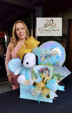 a woman standing next to a teddy bear with balloons and gifts in front of her