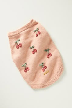 a pink dog sweater with cherries on the front and back, sitting on a white surface