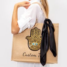 "Tote Bag with Hamsa Hand, Evil Eye Protection Tote Bag, Hamsa bag, Hand of Fatima tote beach bag, custom name Hamsa hand bag, custom totes 🌟About🌟 Looking for the perfect tote bag for you or for your loved ones? Look no further than our Hamsa glittery customized beach tote bags! These unique and stylish bags are perfect for bachelorette parties, bridal showers, or just lounging by the pool with your besties. Each bag is made from high-quality materials and features with a scarf that looks great with everything. The design features the Hasma and your name or custom text in fun and trendy font. Our beach tote bags are available in one size.  Order your tote bag today and get ready to make a splash with your favorite ladies! 🌟These Customized bags are perfect gifts for the bride and their Large Capacity Gold Bag As Gift, Gold Large Capacity Bag For Gift, Large Capacity Gold Bag For Gift, Traditional Tote Bag For Gifts, Traditional Tote Bag As A Gift, Traditional Tote Bag As Gift, Handmade Black Canvas Bag As Gift, Handmade Black Canvas Bag Gift, Handmade Black Canvas Bag For Gift