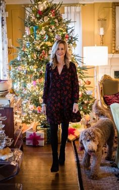 a woman standing in front of a christmas tree