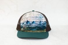 This semi-round brimmed trucker hat features my mountain range painting on a topographic map. Mesh back and adjustable strap. Bridger Range in Montana. Ethically made in Canada. See shop for other hat options. Mountain Range Painting, Hiking Hat, Topographic Map, Mountain Range, Brim Hat, Outdoor Hiking, Trail Running, Trucker Cap, Montana