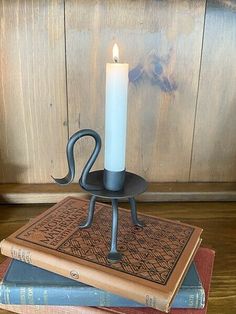 a candle sitting on top of two books next to a book holder with an animal's tail sticking out of it