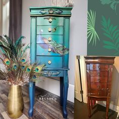 peacock feathers sit on top of an old dresser and next to a gold vase with green leaves