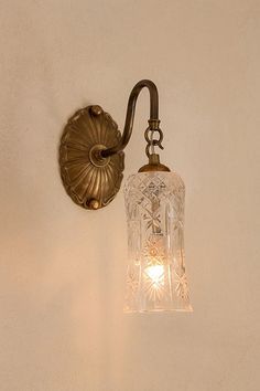 a light that is on the wall next to a white wall with a flower design