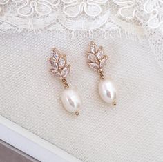 two pairs of pearl and crystal earrings on top of a white lace tablecloth with an embroidered doily