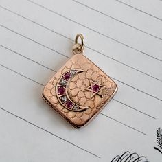 "A wonderful antique locket circa 1895 crafted in 10k rose gold featuring a crescent moon and star on the front cover, set with brightly sparkling old mine-cut diamonds and natural rubies. An engraved shagreen pattern provides a backround for the celestial motif as well as textural interest on the back. Measuring approximately 1\" square the locket opens to reveal space inside for two photos, retaining the original photo holders, and closes securely. The crescent moon, generally interpreted to m Antique Rose Gold Jewelry With Charms, Victorian Crescent Jewelry As Gift, Victorian Crescent Jewelry Gift, Victorian Crescent Jewelry For Gifts, Ruby Locket, Orange Blossom Wedding, Star Locket, Female Strength, Feminine Symbols