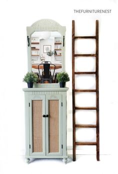 a ladder leaning against a wall next to a cabinet with plants on top and a mirror above it