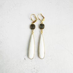 This simple, yet elegant pair features white stones that will truly enchant those around you. GEMSTONE: Agate, moonstone CLOSURE: Gold plated leverback LENGTH: 3" Modern White Brass Jewelry, Minimalist White Brass Jewelry, White Moonstone Earrings For Daily Wear, White Brass Dangle Jewelry, White Brass Drop Earrings, White Teardrop Natural Stone Jewelry, Elegant White Earrings With Natural Stones, White Dangle Earrings With Natural Stones, White Gemstone Long Drop Earrings