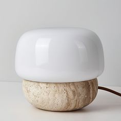 a white lamp sitting on top of a table next to a wooden object with a cord