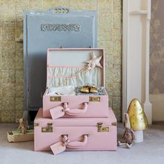 two pink suitcases sitting next to each other on the floor in front of a wall