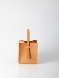 The Cube handbag is a pleasure to carry in your hand or on your wrist. The structural, unique shape offers spacious storage and boasts a hidden clip closure embedded in its handle. The 100% Veg-tanned Vachetta leather bag is intentionally unlined. Crafted with skill by artisans in the Arrhe Studios workshop in Fano, Italy. FIT & SIZING Dimensions: 8 x 8 x 8 in DETAILS Fabric | 100% Veg Tanned Vachetta Italian LeatherColor | NATURALDesigner | ARRHE STUDIOS CARE The leather chosen is subject to ch Office Rectangular Bucket Bag With Leather Handles, Office Bucket Bag With Leather Handles, Modern Brown Box Bag With Handles, Modern Square Box Bag With Handles, Modern Square Leather Bucket Bag, Modern Leather Bucket Box Bag, Bucket Bag With Leather Top Handle For Gift, Bucket Bag With Leather Handles As A Gift, Bucket Bag With Leather Top Handle As A Gift