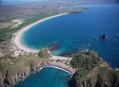 an aerial view of the ocean and coastline near a small island in the middle of the ocean