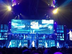 a group of people standing on top of a stage in front of an audience at a concert