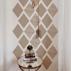 a table with books and a lamp on it in front of a geometric wallpaper