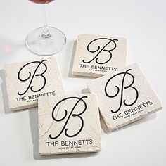 four personalized stone coasters with the letter b on them and a glass of wine