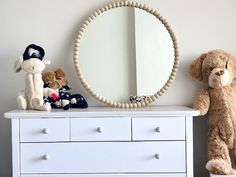 two stuffed animals sitting on top of a white dresser next to a mirror and toy dogs