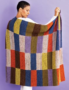 a woman is holding up a multicolored blanket