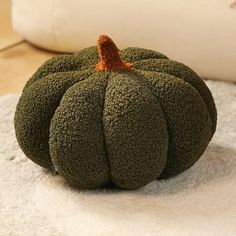 a green pumpkin sitting on top of a white rug