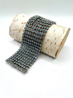 "Add some glam to your look with this magnificent mid-century piece! Rows and rows of round, sparkling, faceted blue crystal rhinestones, prong set in a silver, movable setting. The bracelet measures 6.5\" long (small to medium) and 1.75\" wide. The closure is a slide lock clasp adorned with two additional blue rhinestones. Original safety chain present and functional as well. The bracelet is comfortable and would add a beautiful touch to many different looks!  **All jewelry will arrive in a box with a simple bow tie, so it safely ships and is ready to store or gift. **Please view all photos carefully as they are the exact item you will receive and are an important part of the description. Please note computer monitors vary in the way colors are seen.  **Please keep in mind that most of th Mid Century Glam, 1950s Bracelet, Simple Bow, Glam Jewelry, Slide Lock, Safety Chain, Statement Bracelet, Blue Rhinestones, Color Box