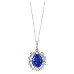 A simple floral motif pendant necklace showcasing a vibrant 2.45-carat oval cut tanzanite, surrounded by 0.74 carats of 62 accent round diamonds. Made in 18 karats white gold. Style available in different price ranges. Prices are based on your selection of the 4C’s (Carat, Color, Clarity, Cut). Please contact us for more information. Flower Pendant Necklace, Flower Pendant, Halo Diamond, Tanzania, Oval Cut, Floral Motif, Round Diamonds, Jewelry Necklace Pendant, Diamond Necklace