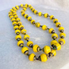 Vintage Yellow Paper Bead Necklace Colorful Handmade African Maximalist Bright 38" Gorgeous handmade paper bead necklace in bright yellow. The yellow paper beads are accented with dark iridescent glass seed beads. Perfect for maximalist dressing to add an unusual detailed necklace, worn alone or in layers. Good vintage condition. Long length that has a small screw closure, allowing the necklace to be worn doubled up. Measures 38" long x 0.5" wide beads Thanks Adjustable Yellow Necklaces With Wooden Beads, Adjustable Yellow Necklace With Wooden Beads, Adjustable Yellow Wooden Beads Necklace, Artisan Yellow Necklaces With Wooden Beads, Artisan Yellow Necklace With Wooden Beads, Yellow Wooden Beads For Jewelry Making, Artisan Yellow Beaded Necklace With Wooden Beads, Yellow Artisan Necklace With Large Beads, Artisan Yellow Necklace With Large Beads