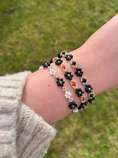 Handmade Black Beaded Flower Bracelet with gold colour findings. Adjustable bracelet available in three variations: -Black and White -Black and Red -Black Please select your chosen colour from the menu when placing your order. Bracelet fits sizes between 16-19cm with use of extender chain. Please note some threads may be visible as this is a handmade product. Ensure to keep this piece out of water and avoid contact with fragrances and lotions as this can make the colours fade. Please drop me a m Black Flower Beaded Bracelets For Gift, Red Flower Beaded Bracelet, Black Flower Beaded Bracelet, White Flower-shaped Beaded Bracelets, Delicate Flower-shaped Beaded Bracelets, Daisy Jewelry, Floral Accessories, String Bracelet, Flower Bracelet