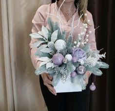 a woman holding a box with flowers and greenery