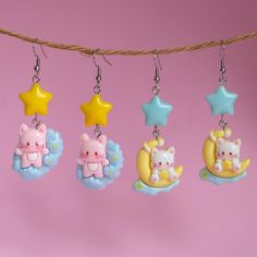 four little charms hanging from a string on a pink background with stars and moon in the sky