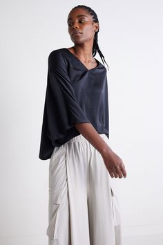 A black batwing style top features wide, flowing sleeves that drape elegantly for a relaxed yet stylish silhouette, perfect for an effortlessly chic look in any season. Its versatile design pairs well with pants or skirts, offering comfort and flair for different occasions. V-neckline Oversized sleeves Draped style Relaxed fit Oversized Versatile V-neck Blouse, Versatile Oversized V-neck Blouse, Versatile Black Rayon Tops, Black V-neck Rayon Blouse, Black Rayon V-neck Blouse, Versatile Black Viscose Blouse, Versatile Black Batwing Sleeve Tops, Casual Black Tops With Kimono Sleeves, Sleek Viscose V-neck Top