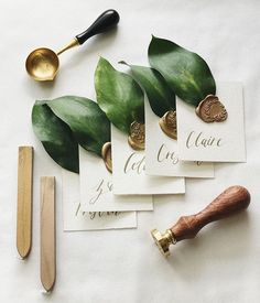 four cards with calligraphy on them next to a pair of scissors and a wooden spoon