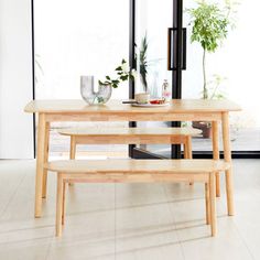 a wooden table with two benches in front of it and a plant on the other side