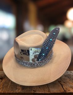 Saddle up in true Western fashion with our Sand Wild Child Felt Hat! Expertly fashioned from high-quality felt, this hat epitomizes countryside allure. Whether you're navigating the city's bustling streets or two-stepping through lively saloons, this teardrop-style hat is your steadfast companion for any occasion. Comes ready-to-wear with a leopard hat belt, Wild Child branding, lucky Joker playing card, and turquoise feather. Western Felt Hats For Winter, Western Winter Felt Hats, Adjustable Western Hat For Town, Western Style Adjustable Hat For Town, Country Style Brimmed Felt Hat For Kentucky Derby, Winter Fedora Hat For Town, Adjustable Fedora Costume Hats For Fall, Fedora Felt Hat For Kentucky Derby, Kentucky Derby Felt Hat With Short Brim