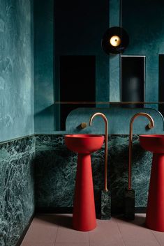 two red pedestal sinks sitting next to each other in a bathroom